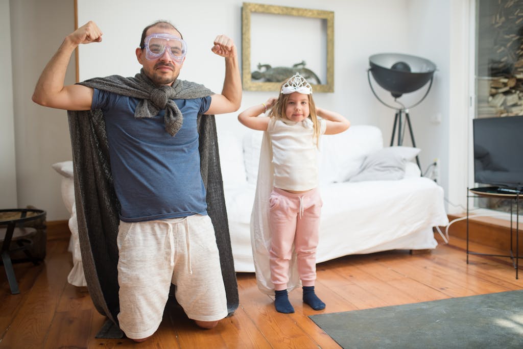Father and daughter enjoying a dress-up game as superheroes in their living room.