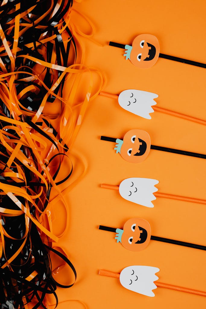 Festive Halloween decorations featuring ghost and pumpkin ornaments on an orange background.