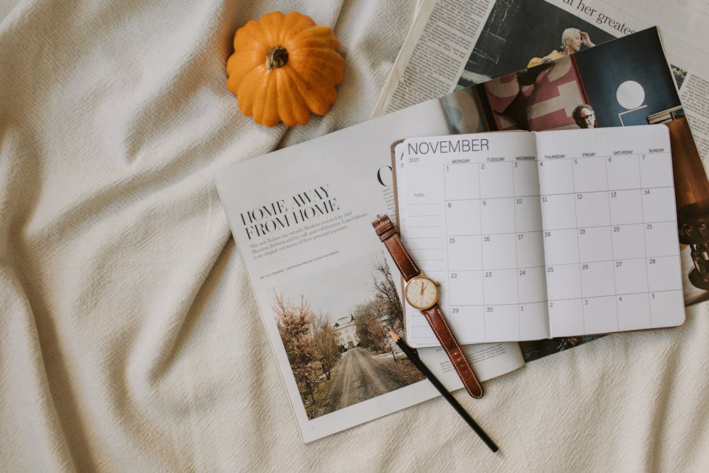Flat lay of a November calendar, watch, and pumpkin reflecting cozy autumn planning vibes.