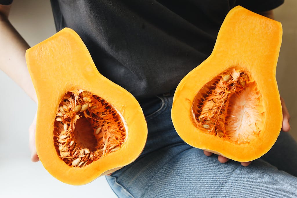 Freshly sliced butternut squash held in hands, showcasing vibrant orange flesh.