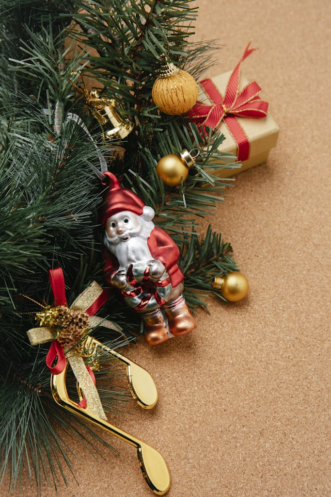 From above of Christmas composition of green fir branch decorated with small bright baubles and little Santa