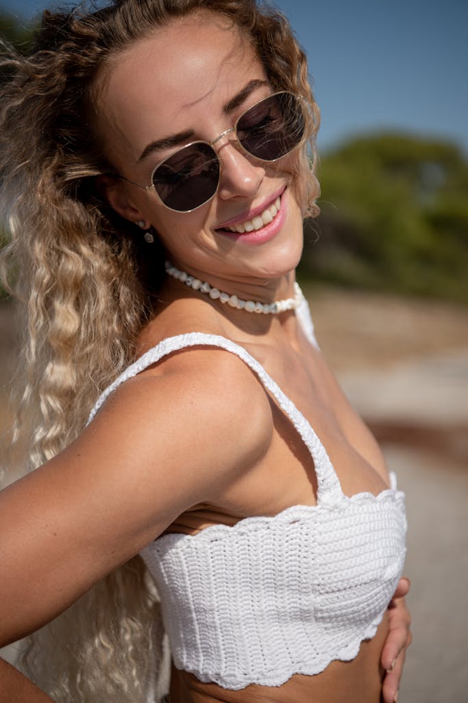 Happy woman with sunglasses enjoying a sunny day at the beach in summer.