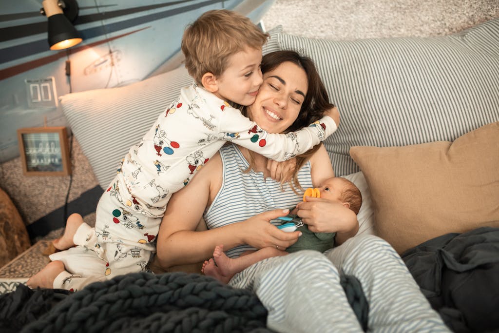Loving mother hugging her children on a cozy bed in a warm home setting.
