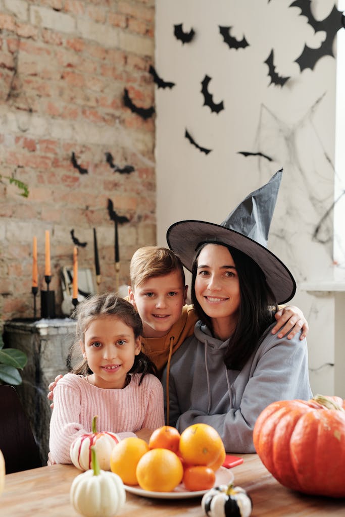 Mother and children enjoy Halloween together with decorations and pumpkins indoors.