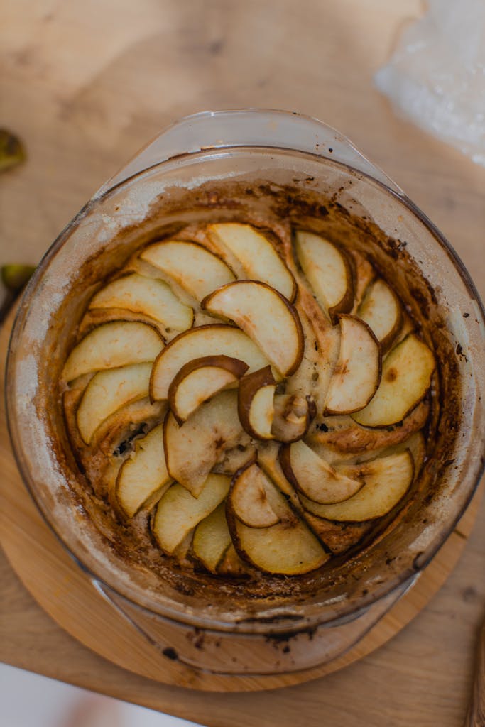 Overhead view of homemade apple tart in glass baking dish on wooden table.