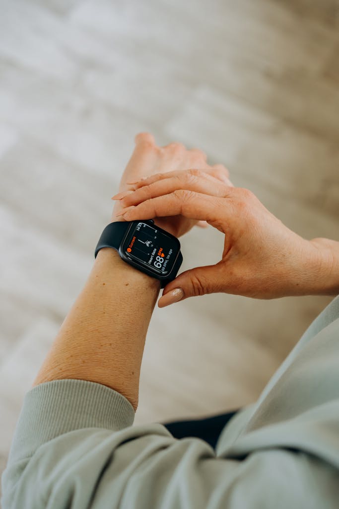 Person interacting with a smartwatch, measuring fitness and heartbeat indoors.