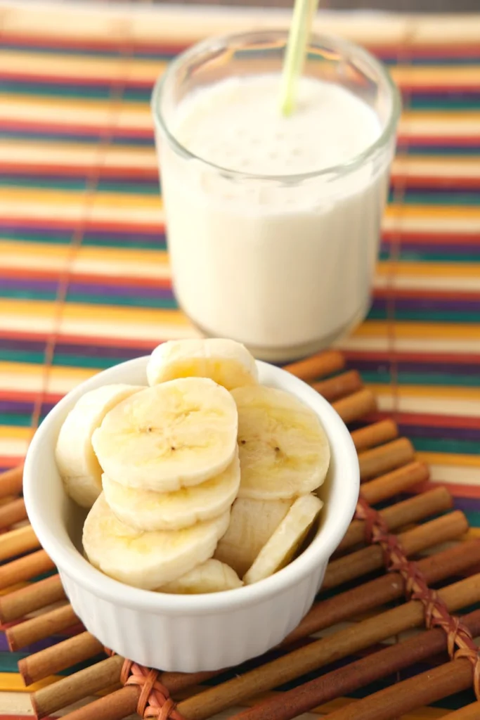 a bowl of sliced banana and a glass of milk
