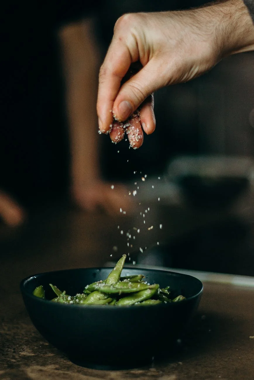 person seasoning green beans with salt