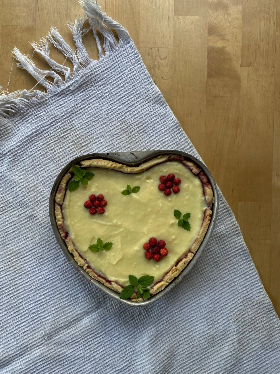 a tart with raspberries and mint leaves
