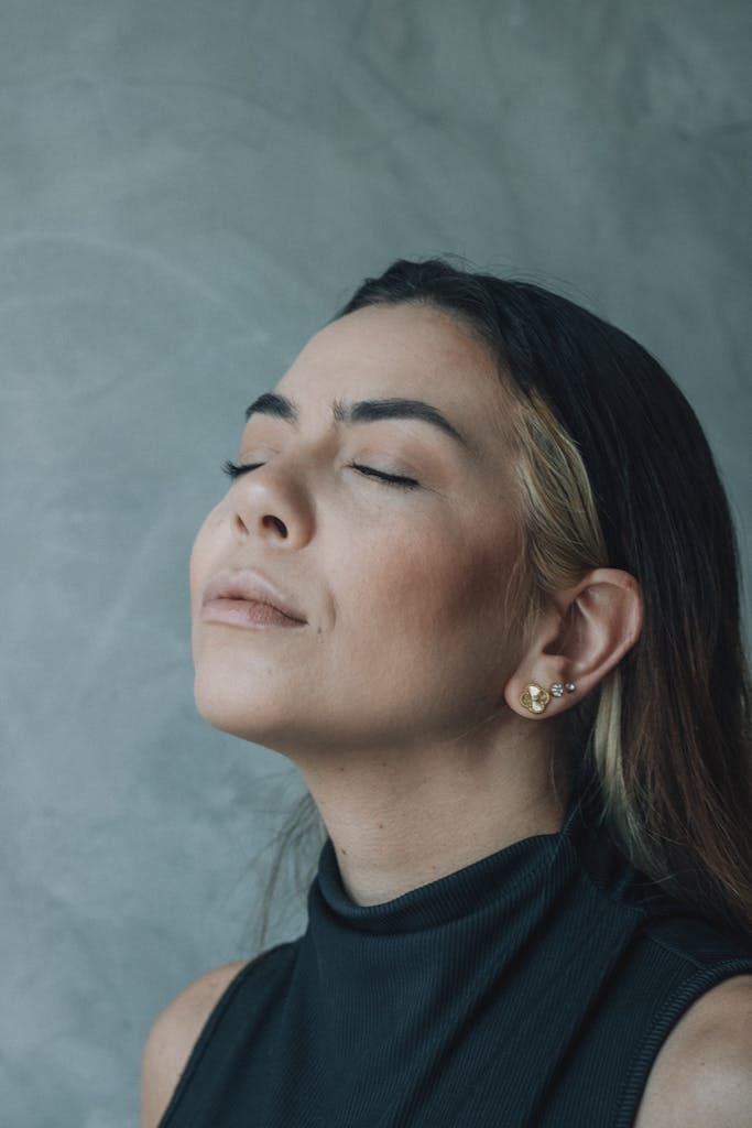Portrait of a relaxed woman meditating with eyes closed against a textured wall.