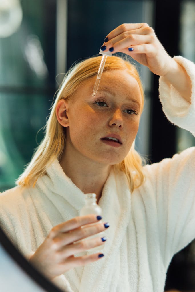 Portrait of a woman using a dropper to apply skincare serum indoors, practicing self-care.
