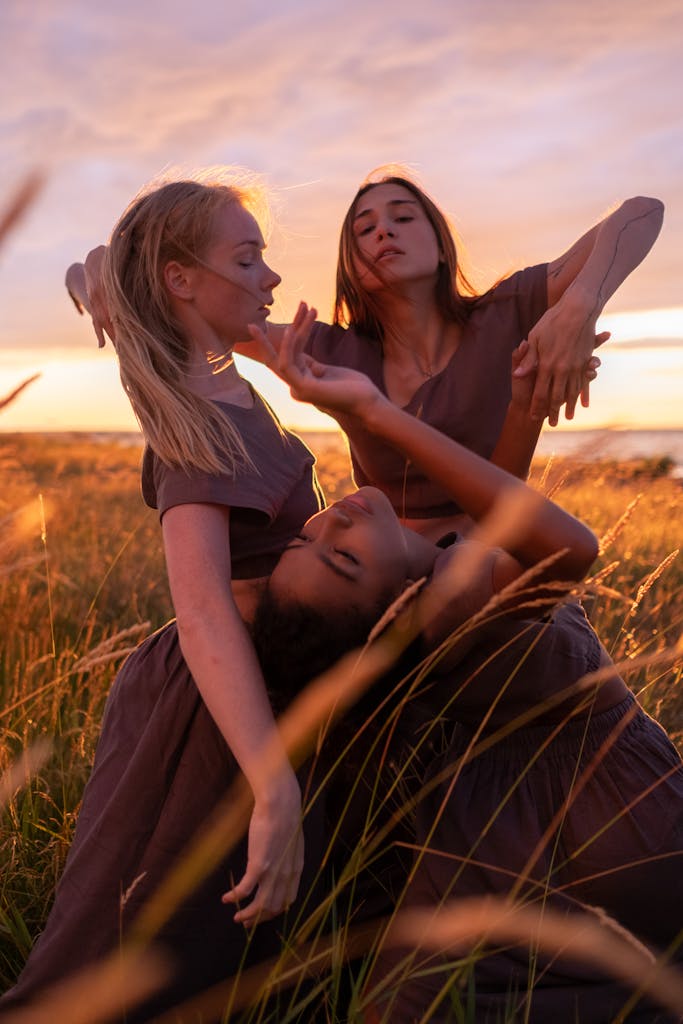 Three women dance gracefully in a sunlit field, embracing diverse beauty.