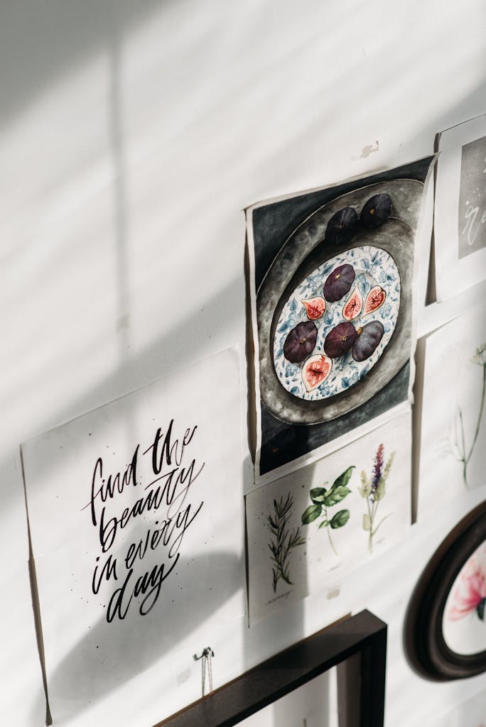 Wall adorned with watercolor paintings and calligraphy in natural light.