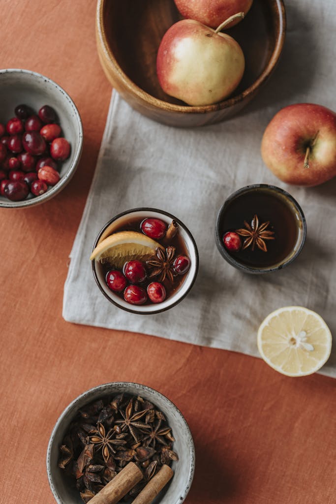 Warm flat lay of mulled wine ingredients with apples, cranberries, and spices.