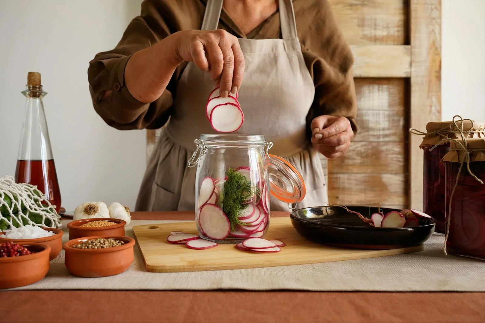 A woman preparing pickled radishes, showcasing ingredients in a rustic kitchen setting.