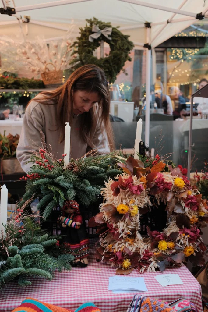 A woman creates festive wreaths at a vibrant outdoor market in Madrid.