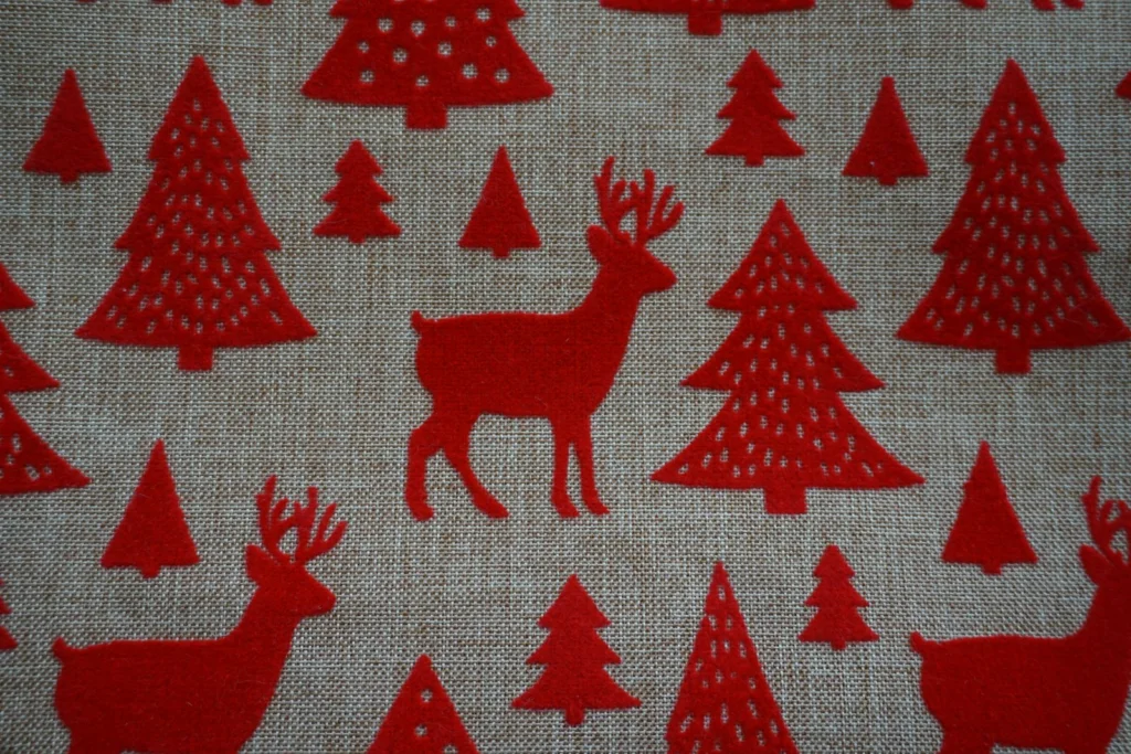 a close up of a red fabric with trees and deer
