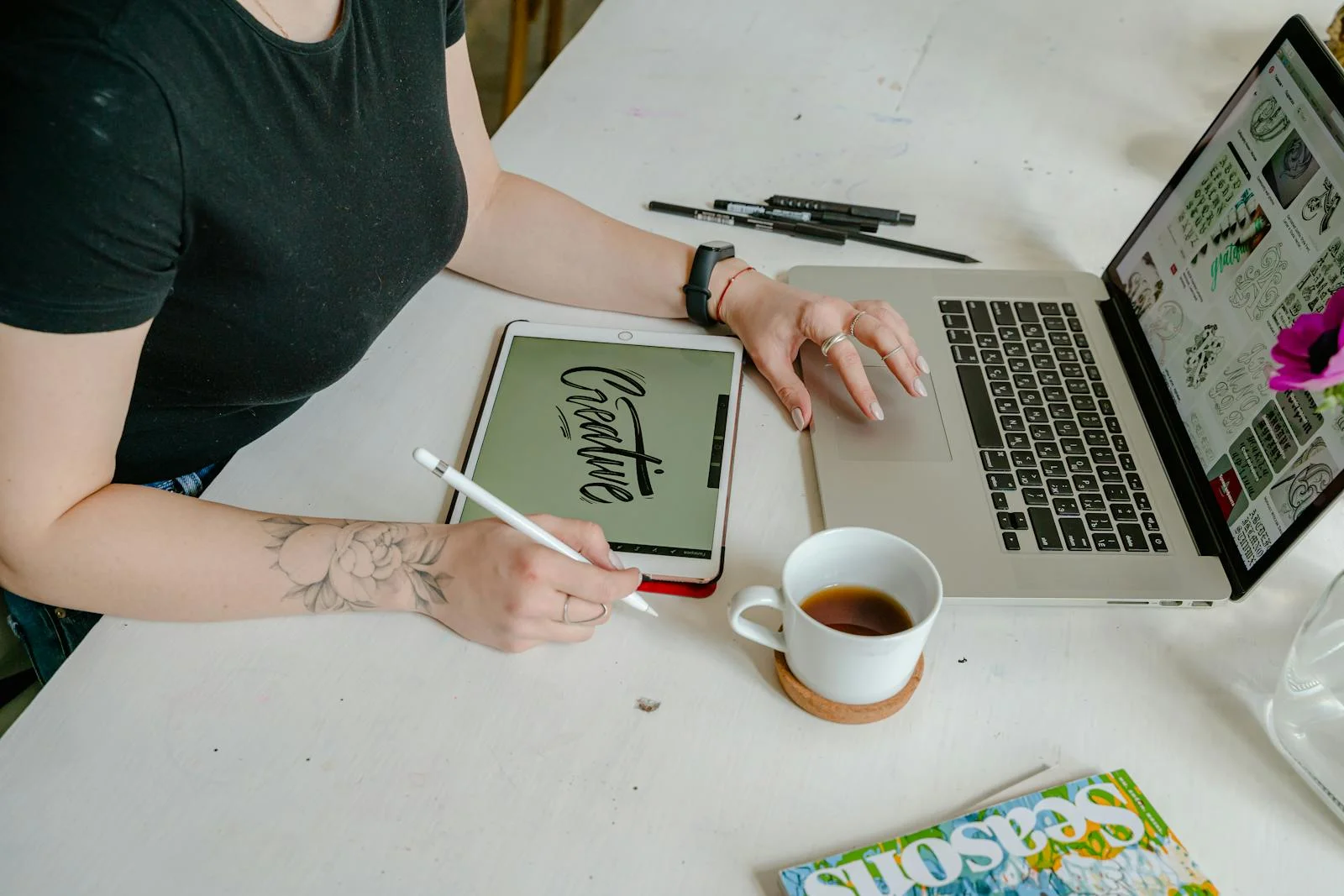 Woman working on digital design with tablet and laptop in a creative office setting.