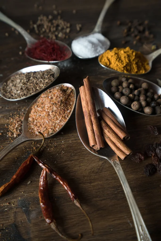 A vibrant collection of spices displayed creatively in spoons on a wooden surface.