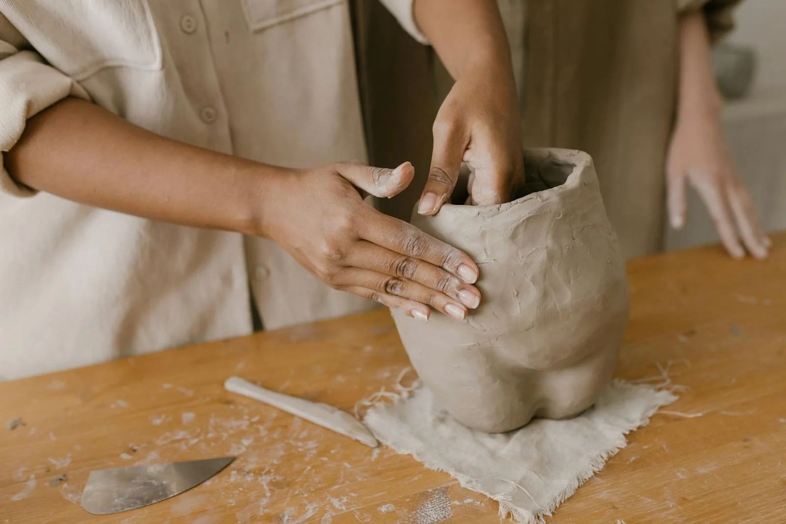 Artisan crafting a clay pot with hands in a pottery workshop. Creative pottery making process.