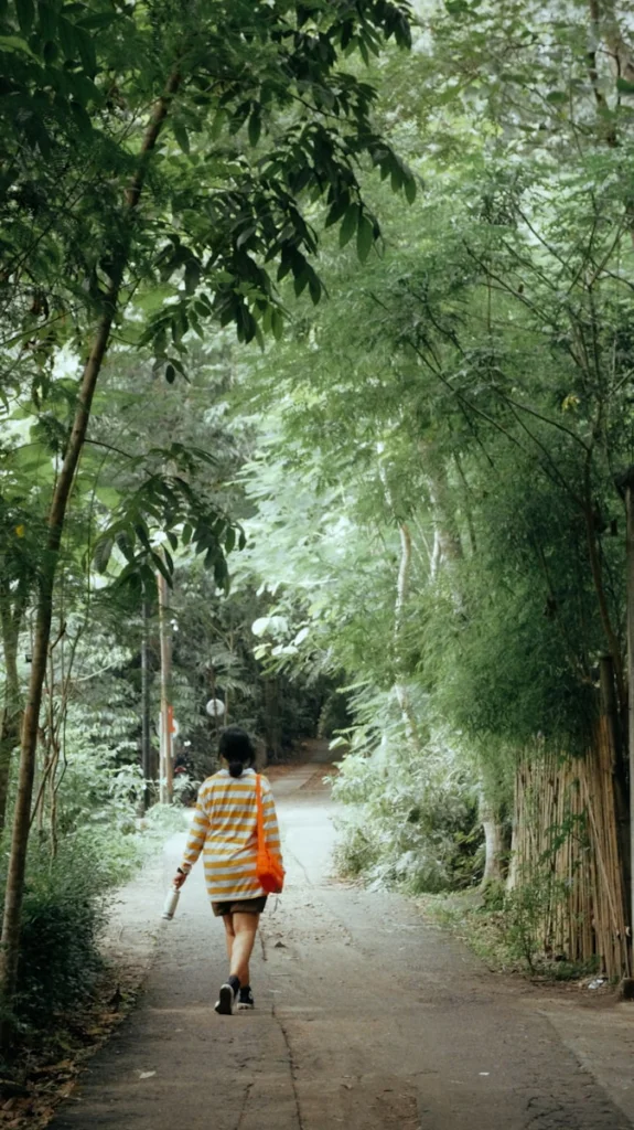 a woman walking down a dirt road in the woods