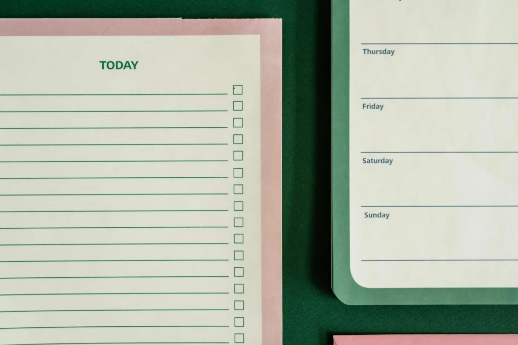Flat lay of planners and stationery on a green background for organizing tasks and schedules.