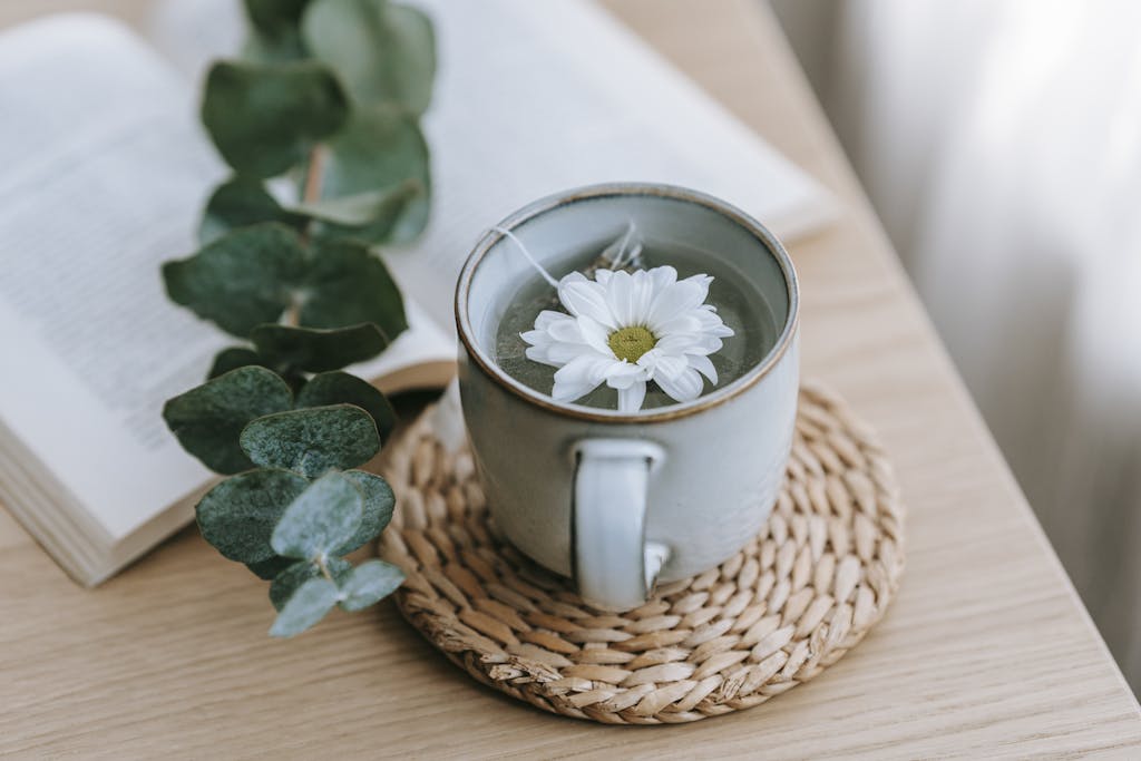 A delicate chrysanthemum flower floats on herbal tea in a cozy indoor setting.