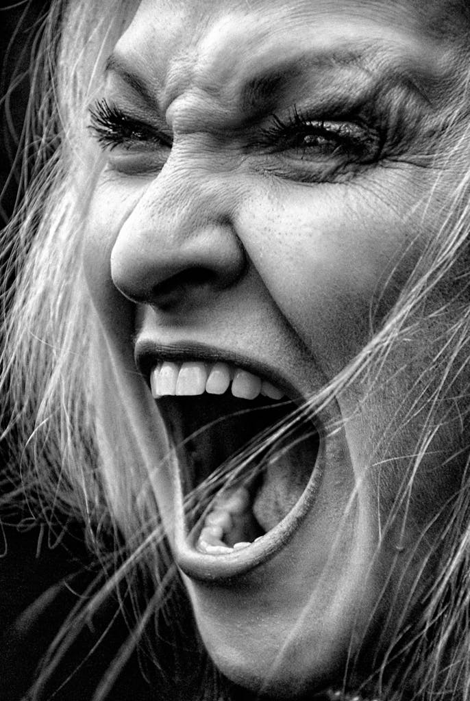 A dramatic black and white close-up of a woman's intense shout, showcasing raw emotion.