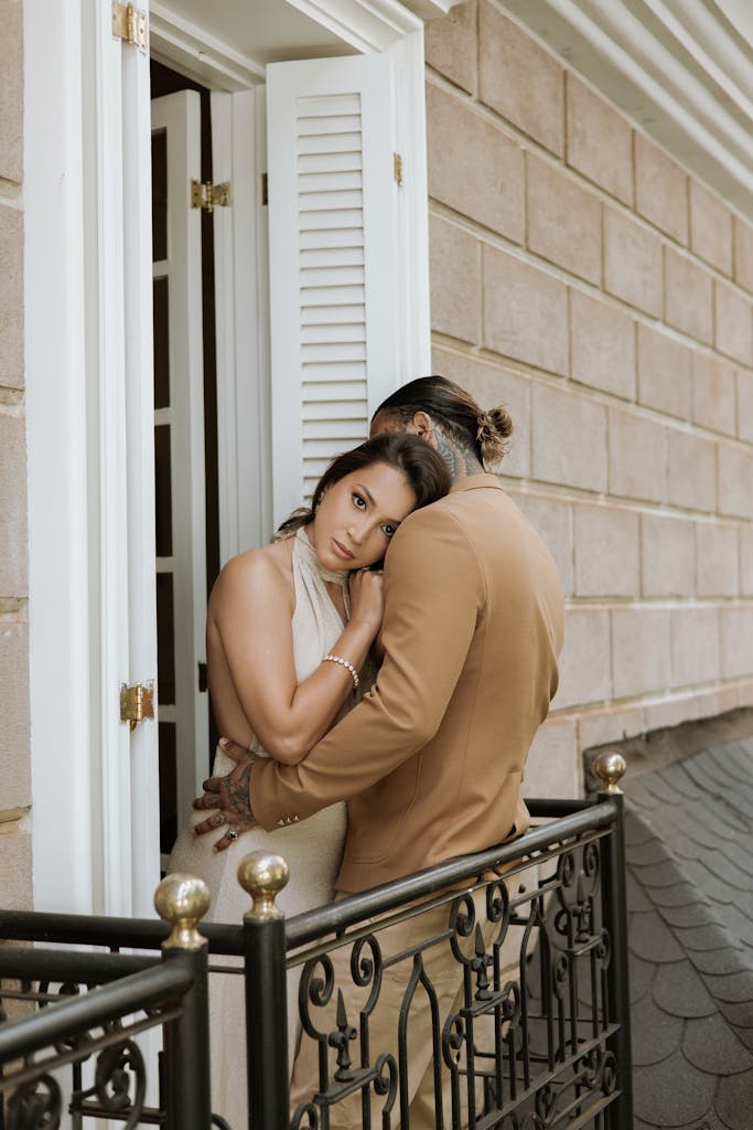 A sophisticated couple embraces on a sunny balcony, exuding a romantic and elegant vibe.