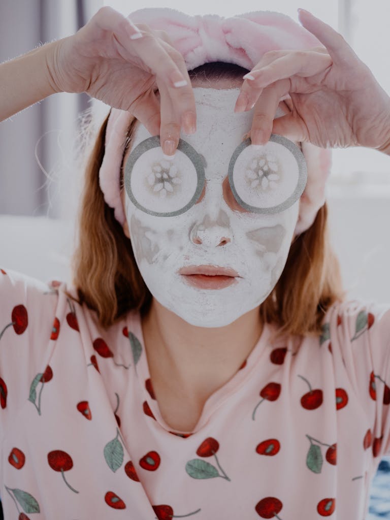 A woman with a skincare mask holding cucumber slices over her eyes for relaxation.