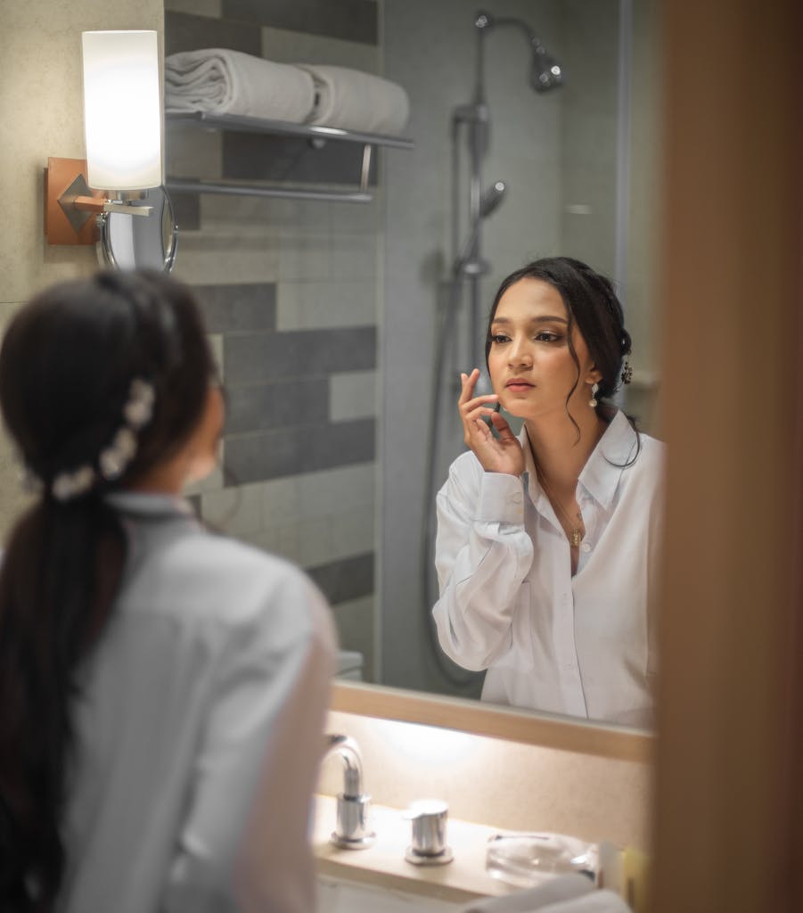 A young woman in a modern bathroom, looking at her reflection in the mirror, Denpasar, Bali.