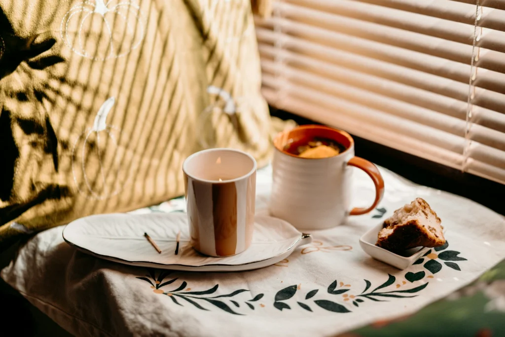 Two mugs and a pastry on a decorative tray.