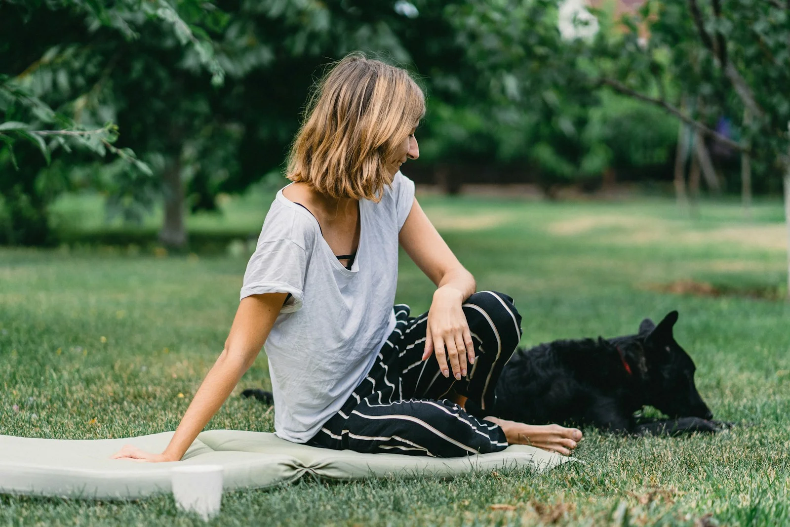 woman sitting on ground beside black dog