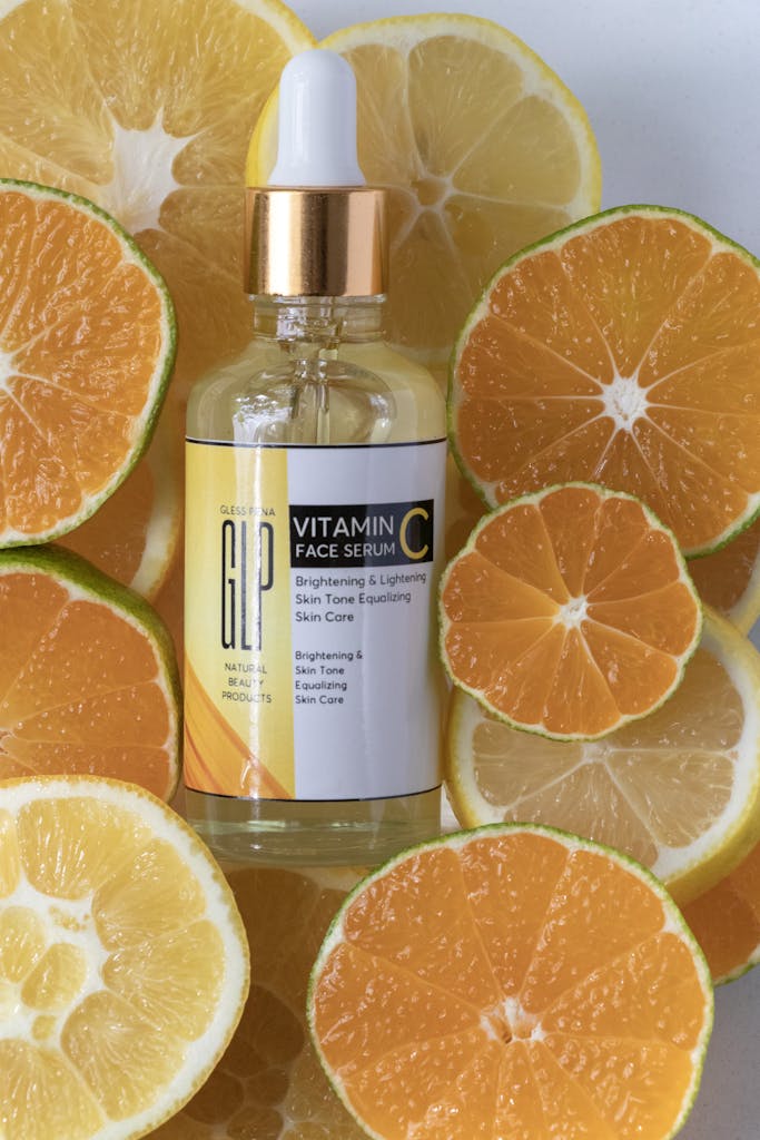 Brightening vitamin C serum surrounded by fresh sliced citrus fruits in a studio setting.