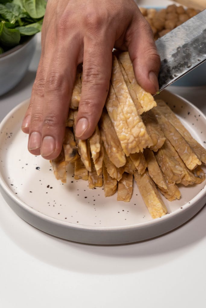 Close-up of tempeh slices being cut on a plate. Perfect for vegan recipes.