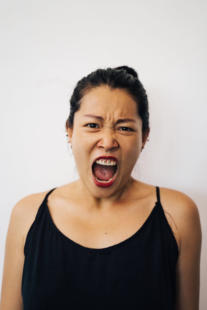 Close-up portrait of a woman expressing intense emotion by yelling. Highlighting facial features and expressions.