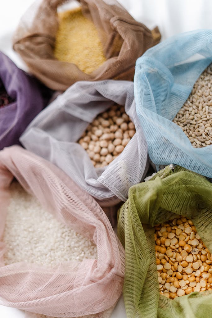 Colorful reusable bags filled with assorted grains and legumes, promoting eco-friendly food storage.