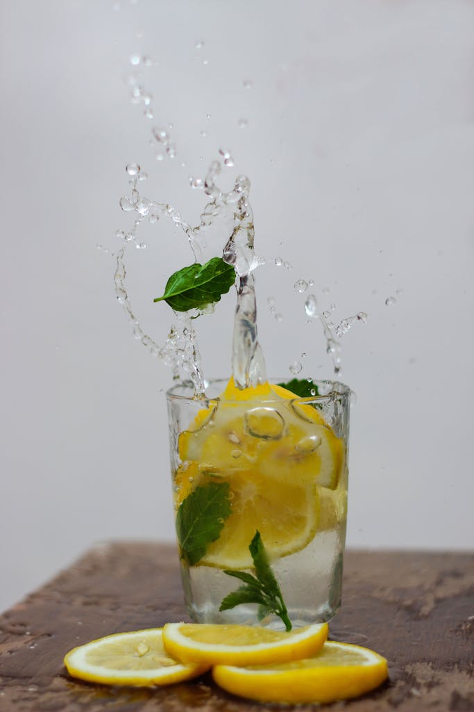 Dynamic shot of lemon and mint slices splashing in water, a refreshing still life.