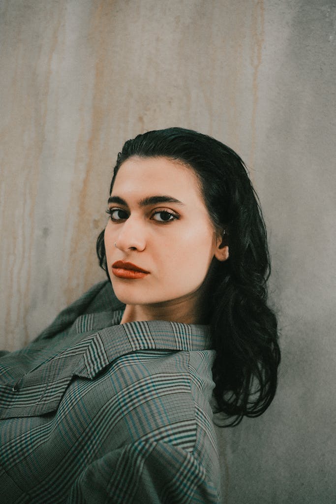 Elegant portrait of a woman in dramatic lighting against a textured wall.