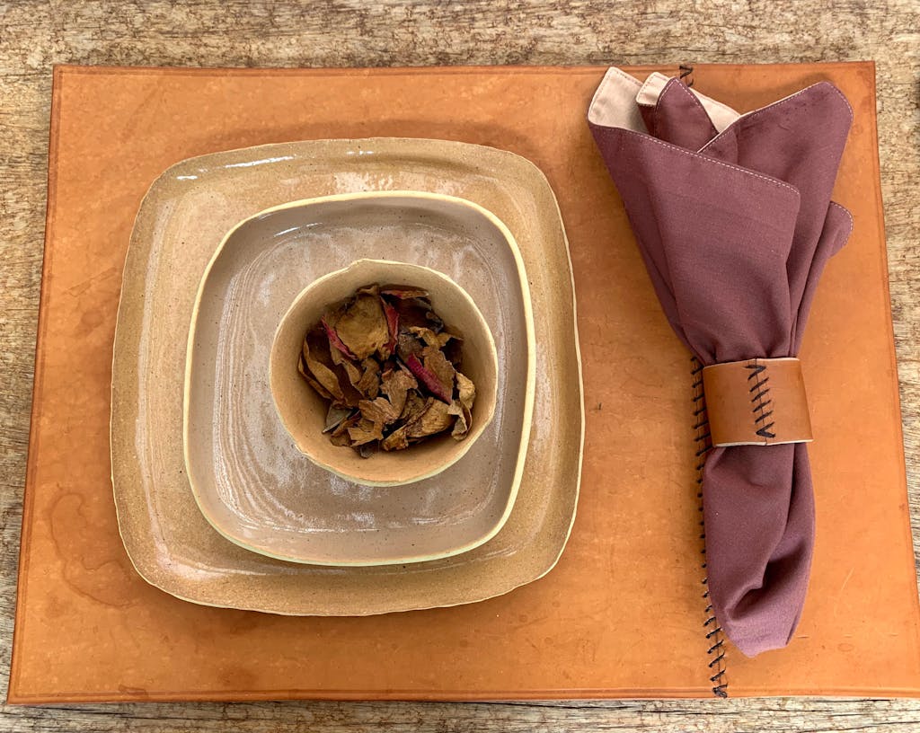 Elegant still life of a rustic table setup featuring stacked ceramic plates and a rolled napkin.