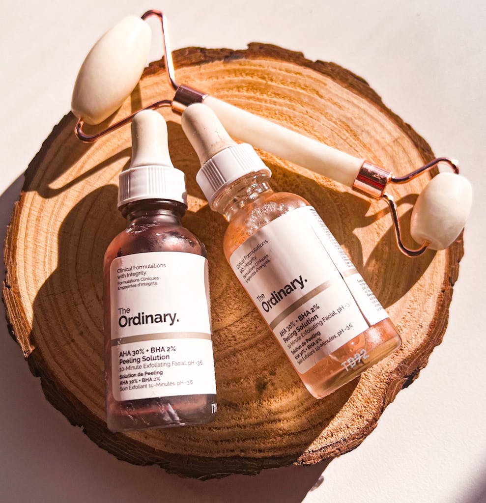 Flat lay of skincare products and facial roller on natural wooden slice for beauty and self-care.
