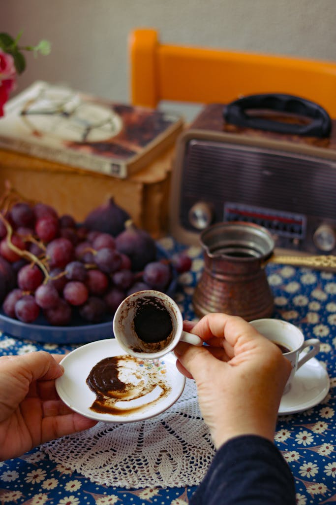 Hands reading coffee grounds in a vintage setting with grapes.
