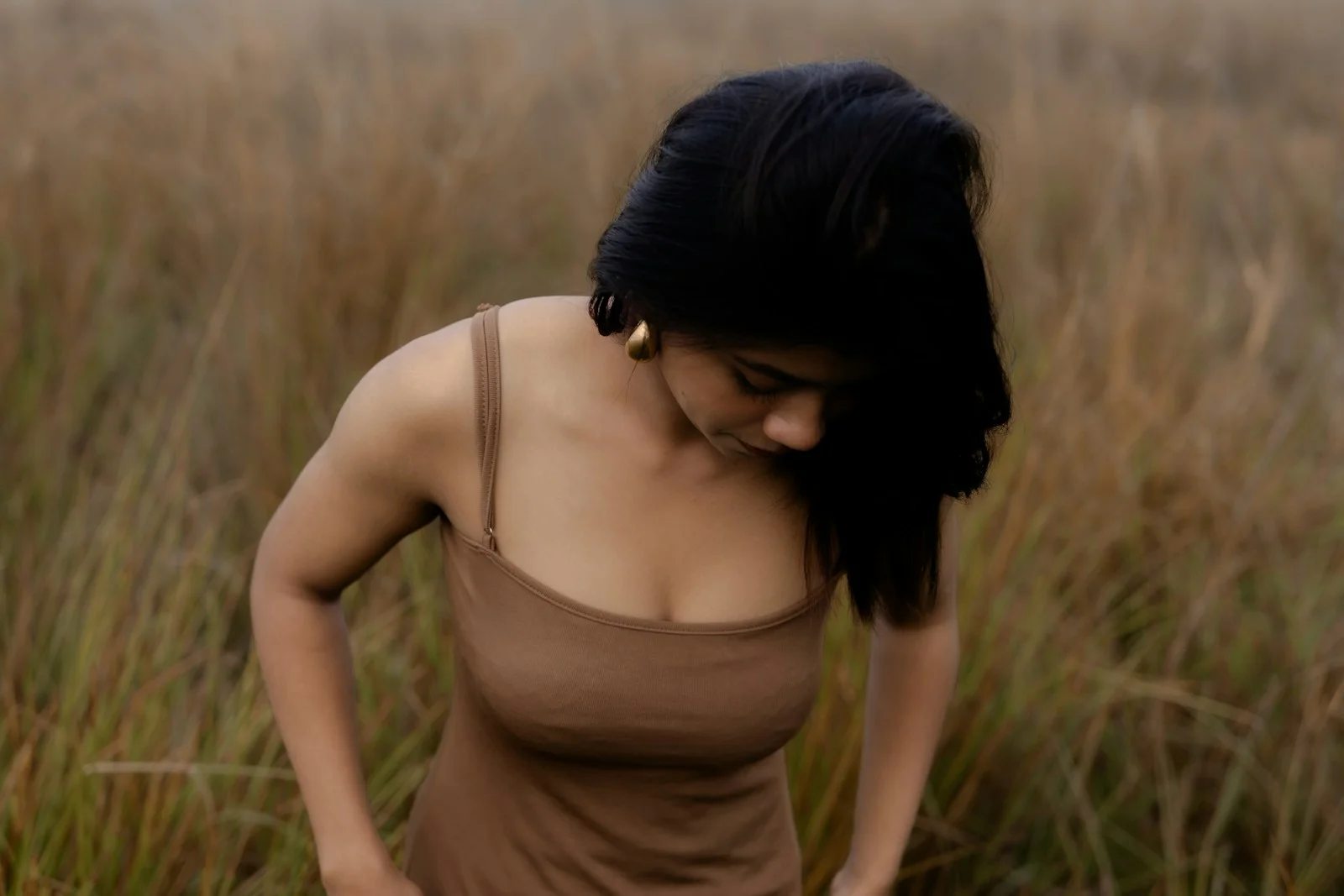 A woman stands in a field of tall grass.