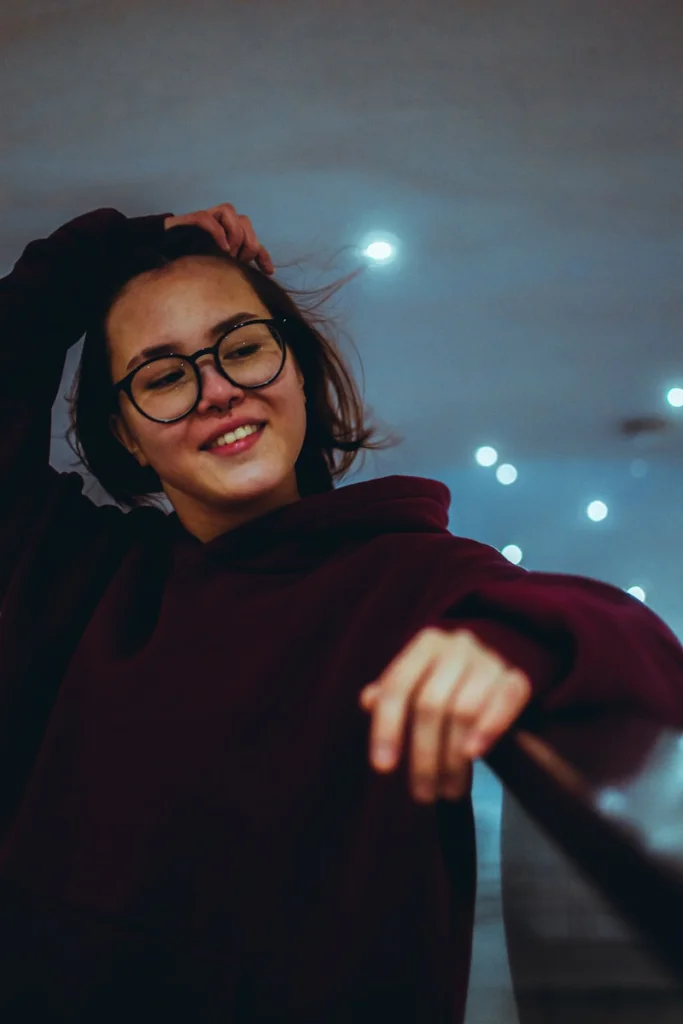 a woman wearing glasses and a hoodie posing for a picture