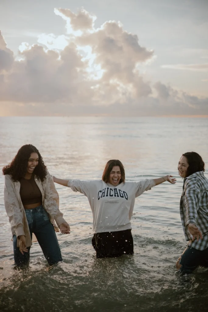 three women standing in the water with their arms outstretched