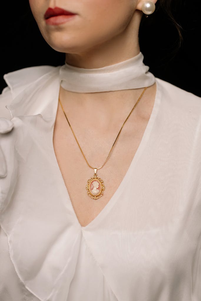 Portrait of a stylish woman wearing an elegant gold cameo necklace and white blouse, capturing vintage elegance.