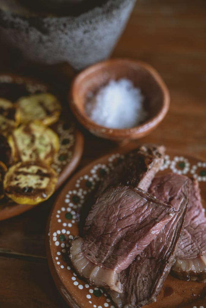 Sliced steak served with grilled vegetables and sea salt on rustic plates.