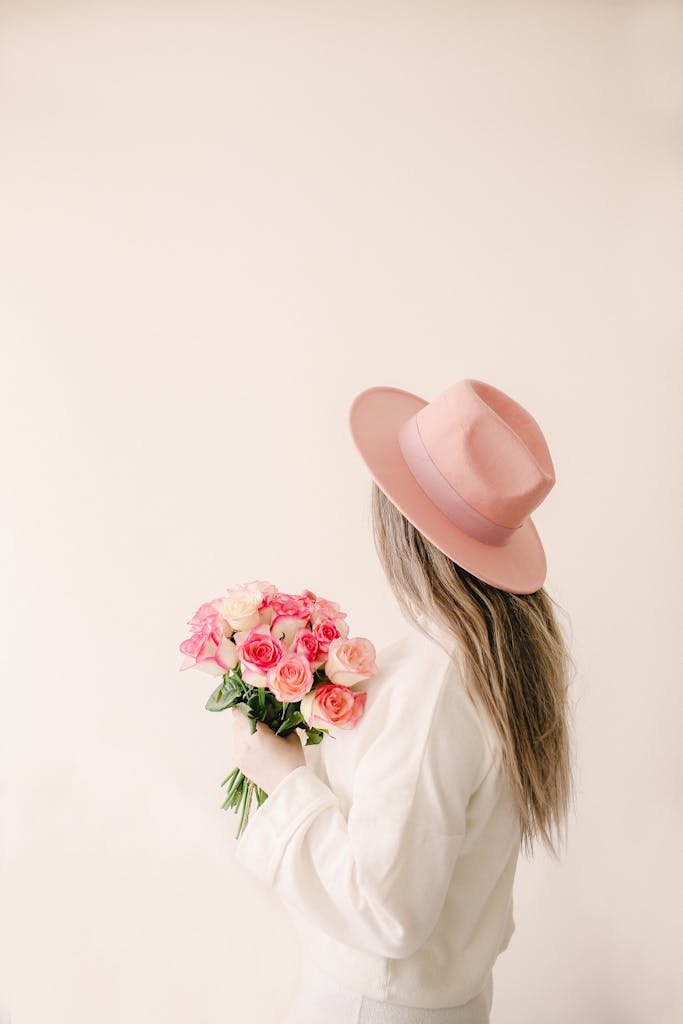 Stylish woman in pink hat holding a bouquet of roses, perfect for spring inspiration and floral themes.