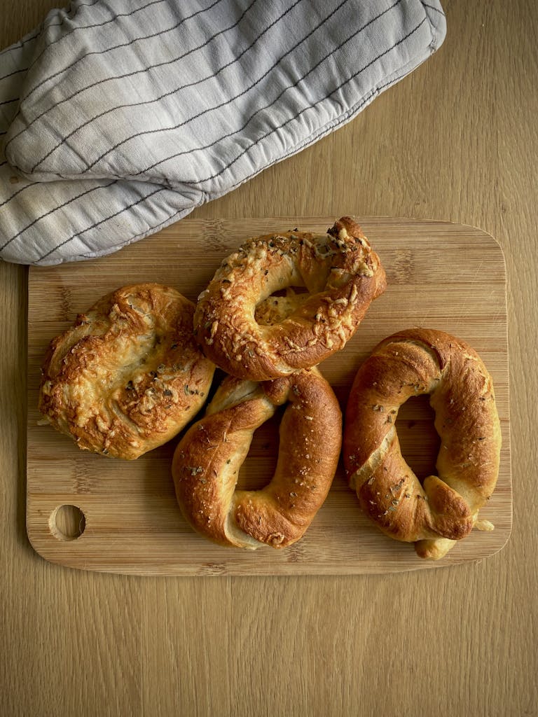 Top view of baked bagels on a wooden board with a striped cloth.