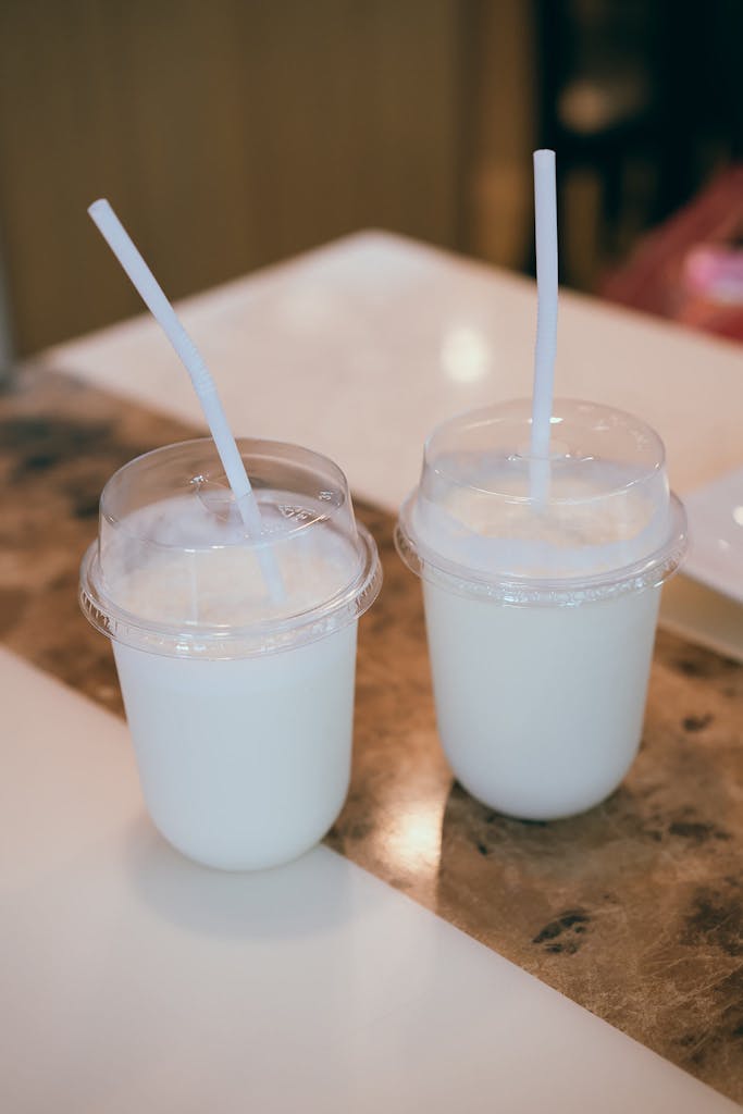 Two plastic cups of creamy lassi on a table, perfect for a healthy refreshment.
